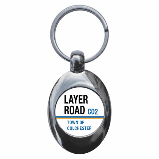 A picture of the front of the product, titled Layer Road CO2 Colchester Road Sign Metal Keyring With Trolley Coin